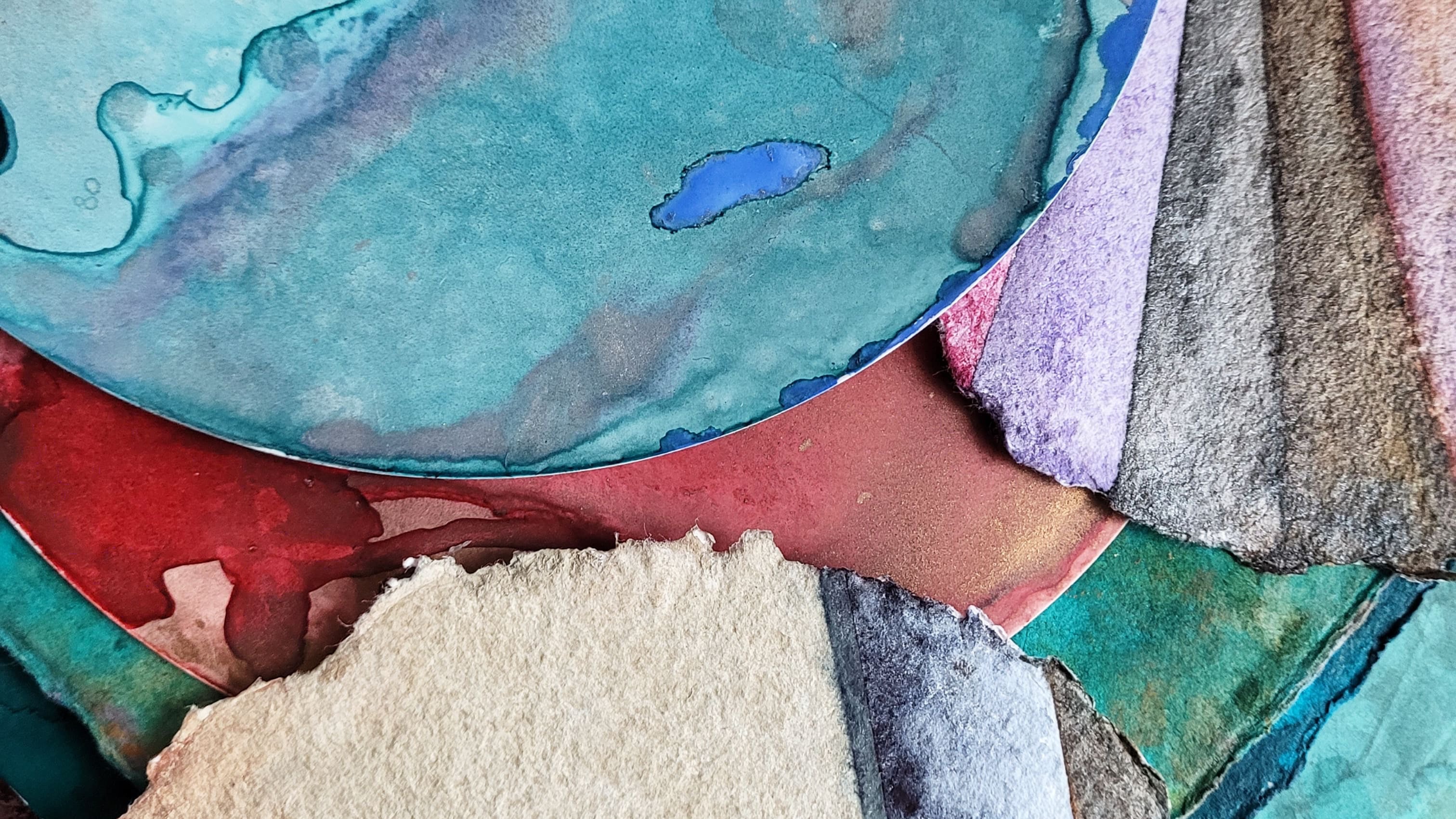 This image shows watercolor layers in a pile of paintings by Kat Furtado. Most of these are round unfinished works featuring organic and geometric shapes (triangles and lines). Watercolor splotches are prominent. Featured colors included vibrant turquoise and purple splotches with hints of indigo ink and bits of amber on a round substrate. Under and to the right of the top circle is a magenta, brown and indigo round with triangles. There are bits of tan, teal, and red throughout. 
